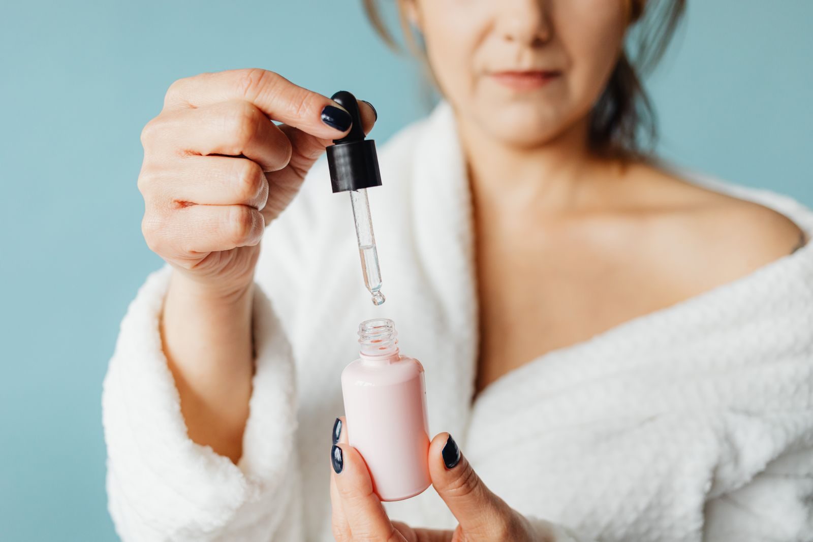 Mujer aplicándose un sérum con cuentagotas como parte de su rutina facial